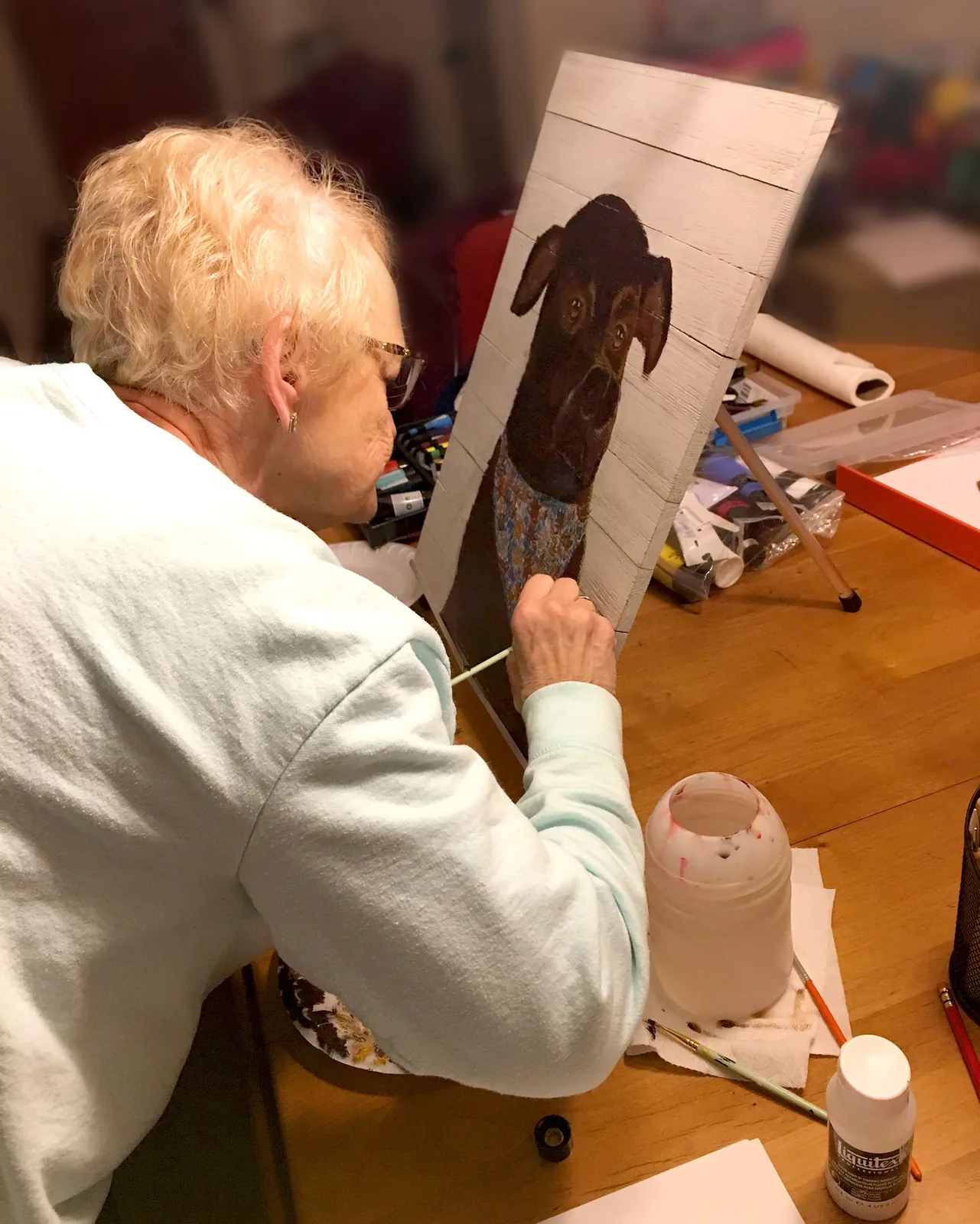 An adult student painting a dog portrait on wood